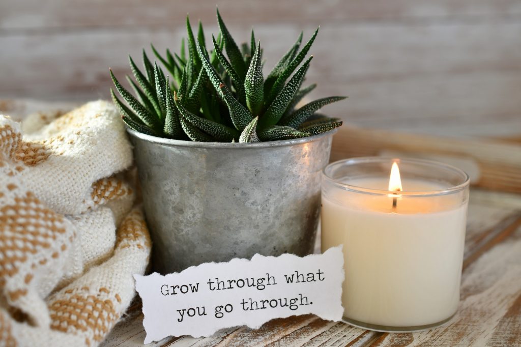 'Grow through what you go through' message sign note with succulent plant & lit candle.