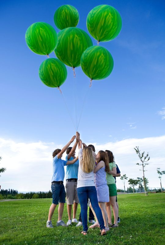 Teenagers holding helium green balloons